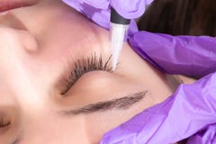 Het schoonheidsspecialistmeisje treft voor het toepassen van permanente eyelinertatoegering voorbereidingen op mooi jong meisje i stock fotografie Het schoonheidsspecialistmeisje treft voor het toepassen van permanente eyelinertatoegering voorbereidingen op mooi jong meisje i stock fotografie