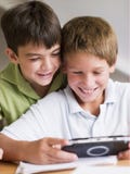 Het Spelen van twee Young Boys met een Hand - gehouden Videospelletje royalty-vrije stock afbeelding Het Spelen van twee Young Boys met een Hand - gehouden Videospelletje royalty-vrije stock afbeelding