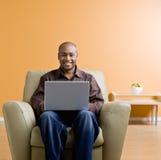 Het typen van de mens op laptop in woonkamer stock fotografie Het typen van de mens op laptop in woonkamer stock fotografie