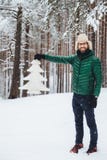 Het verticale portret van positief glimlachend mannetje draagt modieuze warme kleren, houdt witte spar in handen, stelt in de wit stock afbeelding Het verticale portret van positief glimlachend mannetje draagt modieuze warme kleren, houdt witte spar in handen, stelt in de wit stock afbeelding
