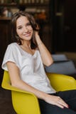 Het verticale schot van mooi meisje gekleed in witte t-shirt en de jeans, hebben gelukkig om camera te bekijken, zitten bij gele royalty-vrije stock afbeeldingen Het verticale schot van mooi meisje gekleed in witte t-shirt en de jeans, hebben gelukkig om camera te bekijken, zitten bij gele royalty-vrije stock afbeeldingen