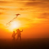 Het vliegen van een vlieger Het meisje en de jongen vliegen een vlieger op het eindeloze gebied Heldere Zonsondergang Silhouetten stock afbeeldingen Het vliegen van een vlieger Het meisje en de jongen vliegen een vlieger op het eindeloze gebied Heldere Zonsondergang Silhouetten stock afbeeldingen