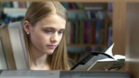 Het vrij jonge meisje kiest een boek in de bibliotheek stock videobeelden Het vrij jonge meisje kiest een boek in de bibliotheek stock videobeelden