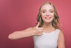 Het vrolijke en aantrekkelijke jongere houdt haar duim tegen en glimlacht Zij is zeer vrolijk Geïsoleerdo op roze royalty-vrije stock fotografie Het vrolijke en aantrekkelijke jongere houdt haar duim tegen en glimlacht Zij is zeer vrolijk Geïsoleerdo op roze royalty-vrije stock fotografie