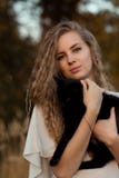 Het vrolijke, gelukkige en glimlachende meisje met perfecte glimlachliefkozing en gehouden zwarte kat dient binnen de zomer, de l Stock Fotografie Het vrolijke, gelukkige en glimlachende meisje met perfecte glimlachliefkozing en gehouden zwarte kat dient binnen de zomer, de l Stock Fotografie