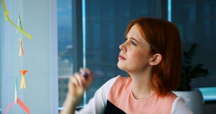 Het vrouwelijke uitvoerende schrijven over kleverige nota over glasraad stock footage Het vrouwelijke uitvoerende schrijven over kleverige nota over glasraad stock footage