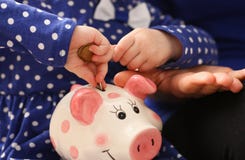 Het wapen die van het kindmeisje muntstukken zetten in piggybank royalty-vrije stock afbeelding Het wapen die van het kindmeisje muntstukken zetten in piggybank royalty-vrije stock afbeelding