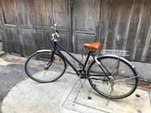 Het zwarte fiets bruine kussen de voordeur van het huis en de oude houten muur is niet geschilderd met een eenvoudig het levensco Royalty-vrije Stock Foto's Het zwarte fiets bruine kussen de voordeur van het huis en de oude houten muur is niet geschilderd met een eenvoudig het levensco Royalty-vrije Stock Foto's
