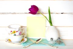 High Tea Time With Stack Of Colorful Teacups, Purple Tulip In Vase, Fork And Spoon, With Light Green Menu Card On White Wood Board Royalty Free Stock Photography High Tea Time With Stack Of Colorful Teacups, Purple Tulip In Vase, Fork And Spoon, With Light Green Menu Card On White Wood Board Royalty Free Stock Photography