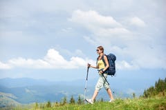 Hiker женщины на травянистом холме, нося рюкзаке, используя trekking ручки в горах стоковое фото Hiker женщины на травянистом холме, нося рюкзаке, используя trekking ручки в горах стоковое фото