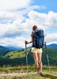 Hiker женщины на травянистом холме, нося рюкзаке, используя trekking ручки в горах стоковая фотография rf Hiker женщины на травянистом холме, нося рюкзаке, используя trekking ручки в горах стоковая фотография rf