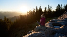 Hiker женщины сидя на валуне в горах на заходе солнца стоковая фотография Hiker женщины сидя на валуне в горах на заходе солнца стоковая фотография