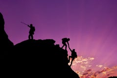 Hikers climbing on rock, mountain at sunset, one of them giving hand and helping to climb.Teamwork , Helps ,Success, winner and Le