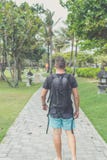 Hintere Ansicht des Mannes mit Rucksack gehend in den Strandpark von Nusa-DUA, Bali-Insel, Indonesien Stockfotos Hintere Ansicht des Mannes mit Rucksack gehend in den Strandpark von Nusa-DUA, Bali-Insel, Indonesien Stockfotos