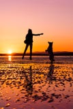 Hipster girl playing with dog at a beach during sunset, silhouettes Royalty Free Stock Images Hipster girl playing with dog at a beach during sunset, silhouettes Royalty Free Stock Images