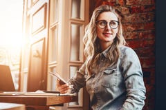 Hipster girl in trendy glasses sits in cafe at table in front of stock photo Hipster girl in trendy glasses sits in cafe at table in front of stock photo