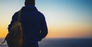 Hipster hiker tourist with backpack looking of amazing seascape sunset on background blue sea, guy enjoying ocean horizon, panoram royalty free stock images Hipster hiker tourist with backpack looking of amazing seascape sunset on background blue sea, guy enjoying ocean horizon, panoram royalty free stock images