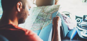 Hipster man looking and point finger on location navigation map in car, tourist traveler driving and hold in male hands europe car stock photo Hipster man looking and point finger on location navigation map in car, tourist traveler driving and hold in male hands europe car stock photo