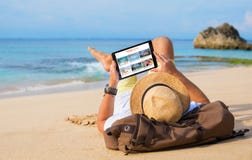 Man reading travel blog on beach stock image Man reading travel blog on beach stock image