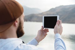 Hipster person holding in hands digital tablet with empty blank screen, man photograph on computer on background nature Royalty Free Stock Photos Hipster person holding in hands digital tablet with empty blank screen, man photograph on computer on background nature Royalty Free Stock Photos