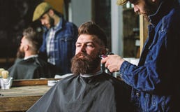 Hipster με τη γενειάδα που καλύπτεται με την τακτοποίηση ακρωτηρίων από τον επαγγελματικό κουρέα στο μοντέρνο barbershop Έννοια κ στοκ εικόνες Hipster με τη γενειάδα που καλύπτεται με την τακτοποίηση ακρωτηρίων από τον επαγγελματικό κουρέα στο μοντέρνο barbershop Έννοια κ στοκ εικόνες