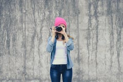 Hipsterflicka i att bekläda för jeans och den rosa hatten som tar fotoet mot den gråa betongväggen Fokus på kamera Stil för modes royaltyfria foton Hipsterflicka i att bekläda för jeans och den rosa hatten som tar fotoet mot den gråa betongväggen Fokus på kamera Stil för modes royaltyfria foton
