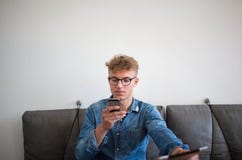 Hipstergrabb som överför meddelandet via mobiltelefonen under arbete på den digitala minnestavlan royaltyfria foton Hipstergrabb som överför meddelandet via mobiltelefonen under arbete på den digitala minnestavlan royaltyfria foton