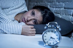 Hispanic woman at home bedroom lying in bed late at night trying to sleep suffering insomnia