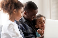 Historietas jovenes afroamericanas felices del reloj de la familia en el ordenador portátil imágenes de archivo libres de regalías Historietas jovenes afroamericanas felices del reloj de la familia en el ordenador portátil imágenes de archivo libres de regalías