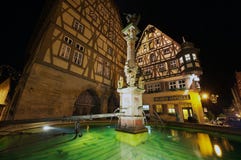 Historische Gebäude mit Brunnen am Vordergrund nachts in Rothenburg Ob Der Tauber, Deutschland lizenzfreie stockfotografie Historische Gebäude mit Brunnen am Vordergrund nachts in Rothenburg Ob Der Tauber, Deutschland lizenzfreie stockfotografie