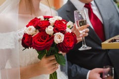 Hochzeitsblumenstrauß von roten und weißen Rosen in der Hand der Braut und des Glases Champagners in der anderen Hand lizenzfreies stockbild Hochzeitsblumenstrauß von roten und weißen Rosen in der Hand der Braut und des Glases Champagners in der anderen Hand lizenzfreies stockbild