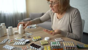 Hogere vrouw die capsules van alle flessen nemen, self-medication, pillenverslaving stock footage Hogere vrouw die capsules van alle flessen nemen, self-medication, pillenverslaving stock footage