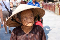 Hoi An Vietnam - NOVEMBER 02, 2011: En äldre vietnamesisk kvinna i en traditionell sugrörhatt royaltyfria bilder Hoi An Vietnam - NOVEMBER 02, 2011: En äldre vietnamesisk kvinna i en traditionell sugrörhatt royaltyfria bilder