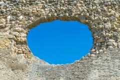 A hole in the stone wall and the blue sky in the background, a ruined wall with a hole. royalty free stock images A hole in the stone wall and the blue sky in the background, a ruined wall with a hole. royalty free stock images