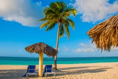 Holguin, Cuba, Playa Esmeralda Paraplu en twee zitkamerstoelen rond palmen Tropisch strand op het Caraïbische overzees Paradijsla stock foto's Holguin, Cuba, Playa Esmeralda Paraplu en twee zitkamerstoelen rond palmen Tropisch strand op het Caraïbische overzees Paradijsla stock foto's