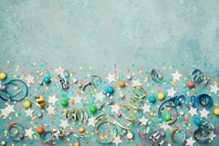 Holiday background decorated colorful confetti, star, candy and streamer on blue vintage table top view. Flat lay. Festive border.