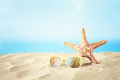 Holidays. sand beach, sunglasses and starfish in front of summer sea background with copy space