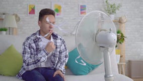 Hombre asiático joven que se sienta delante de una fan de trabajo, el concepto del calor MES lento metrajes Hombre asiático joven que se sienta delante de una fan de trabajo, el concepto del calor MES lento metrajes
