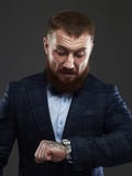 Hombre barbudo en el traje que espera y que mira el reloj imagenes de archivo Hombre barbudo en el traje que espera y que mira el reloj imagenes de archivo