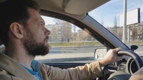 Hombre barbudo que conduce un coche en un día soleado en la ciudad metrajes Hombre barbudo que conduce un coche en un día soleado en la ciudad metrajes