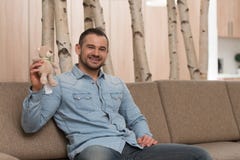 Hombre con el pequeño juguete lindo en el sofá foto de archivo libre de regalías Hombre con el pequeño juguete lindo en el sofá foto de archivo libre de regalías