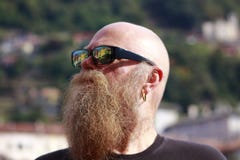 Hombre con la barba larga, miradas de las gafas de sol cuidadosamente imagen de archivo Hombre con la barba larga, miradas de las gafas de sol cuidadosamente imagen de archivo