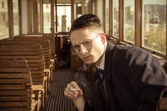 Hombre con los vidrios en un traje que se sienta en un tren de carromatos de madera viejo imágenes de archivo libres de regalías Hombre con los vidrios en un traje que se sienta en un tren de carromatos de madera viejo imágenes de archivo libres de regalías