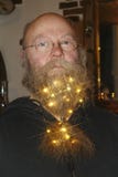 Hombre con vidrios y una cadena de luces, con las estrellas chispeantes en barba foto de archivo libre de regalías Hombre con vidrios y una cadena de luces, con las estrellas chispeantes en barba foto de archivo libre de regalías