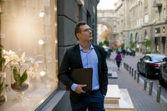 Hombre de negocios acertado en traje con el ordenador portátil en la ciudad fotos de archivo Hombre de negocios acertado en traje con el ordenador portátil en la ciudad fotos de archivo