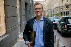 Hombre de negocios acertado en traje con el ordenador portátil en la ciudad imágenes de archivo libres de regalías Hombre de negocios acertado en traje con el ordenador portátil en la ciudad imágenes de archivo libres de regalías