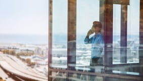 Hombre de negocios dentro del edificio de oficinas que habla en el teléfono móvil Fotos de archivo libres de regalías Hombre de negocios dentro del edificio de oficinas que habla en el teléfono móvil Fotos de archivo libres de regalías