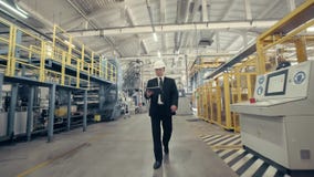 Hombre de negocios en casco que camina a través de fábrica almacen de metraje de vídeo Hombre de negocios en casco que camina a través de fábrica almacen de metraje de vídeo