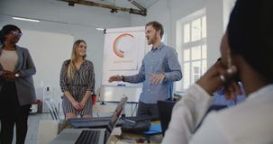 Hombre de negocios enérgico profesional joven que motiva a empleados corporativos multiétnicos felices en la reunión formal de la Hombre de negocios enérgico profesional joven que motiva a empleados corporativos multiétnicos felices en la reunión formal de la