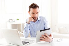 Hombre de negocios joven que trabaja en casa en su tableta imagenes de archivo Hombre de negocios joven que trabaja en casa en su tableta imagenes de archivo